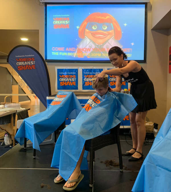 lady cutting kid's hair at fundraising event